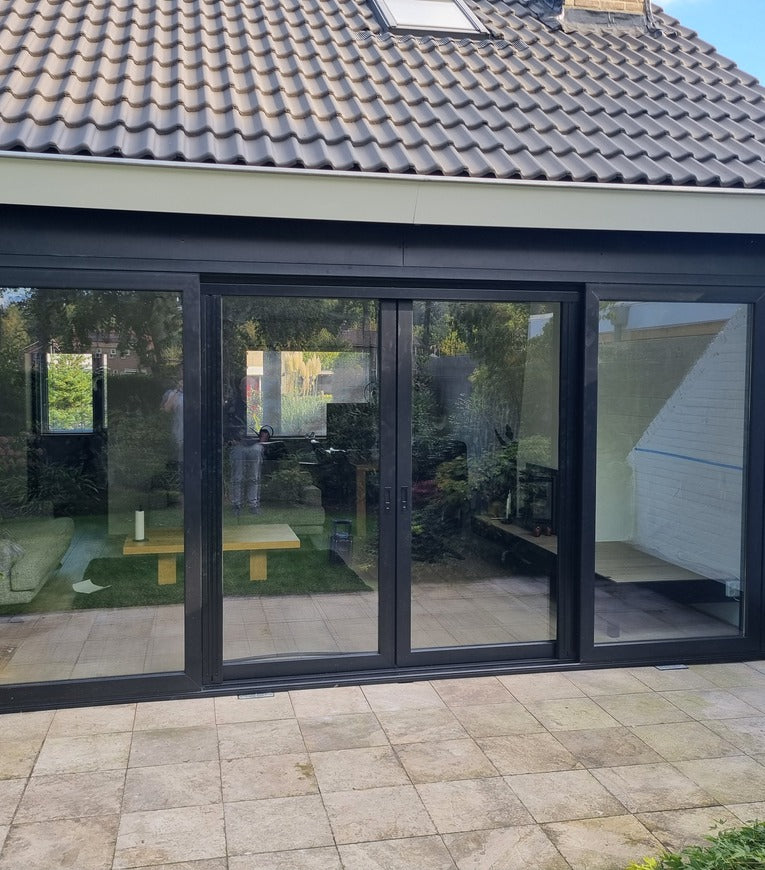 Woning met zwarte kunststof kozijnen en grote glazen schuifpui.