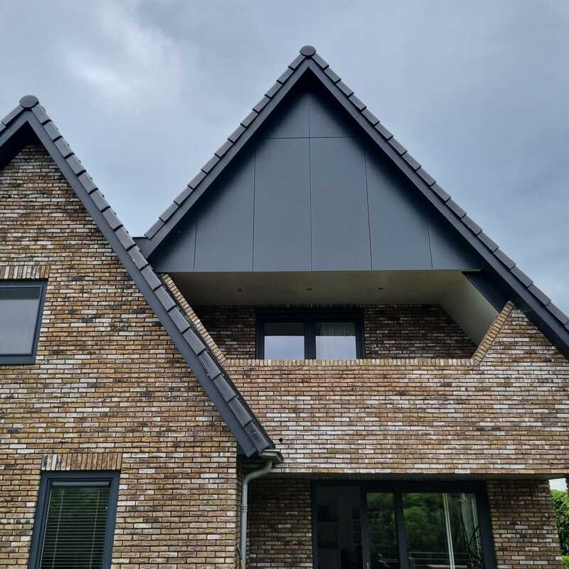 Woning met antraciet kunststof bouwmateriaal als afwerking van de geveltop.