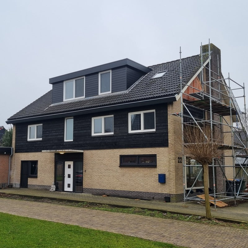 Woning afgewerkt met zwart bouwmateriaal van kunststof rond de gevel en dakkapel.